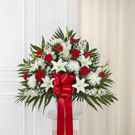 Standing floral spray with red roses, white lilies, and a red ribbon