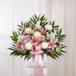 Pink and white floral spray with a ribbon on a stand