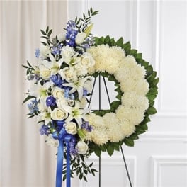 White floral wreath with blue and white flowers on a stand
