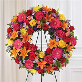 Colorful floral wreath on a black stand with roses and daisies