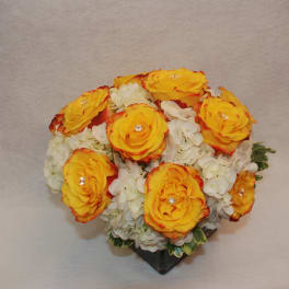 Bouquet of yellow roses with white flowers in a black holder