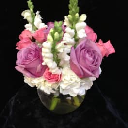 Pink and lavender roses with white snapdragons in a glass vase