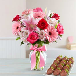 Pink and red mixed bouquet in a glass vase with a pink ribbon