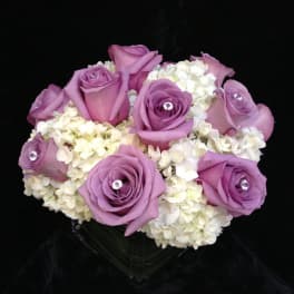 Lavender roses arranged with white hydrangeas in a clear vase