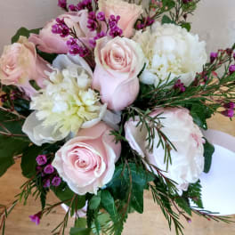 Pink roses and white blooms with purple filler flowers in a bouquet