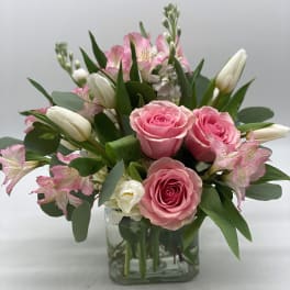 Pink roses and white tulips in a clear glass vase