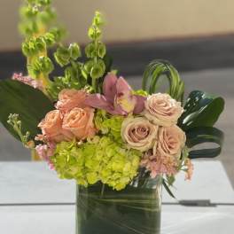 Pink roses and green hydrangeas in a square glass vase