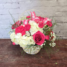 Pink roses and white hydrangeas in a basket with pink ribbon