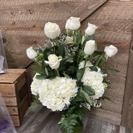 White roses and hydrangeas arranged in a glass vase