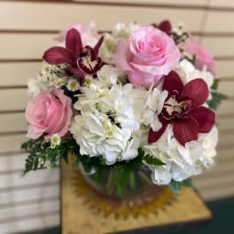 Pink roses and white hydrangeas with burgundy orchids in a glass vase