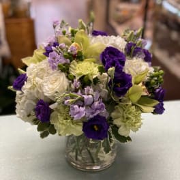 Bouquet of white, purple, and pale yellow flowers in a clear glass vase