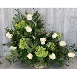 White roses and green blooms arranged in a wicker basket