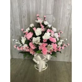Pink and white floral arrangement in a white vase with a ribbon bow
