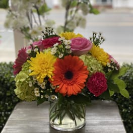Mixed bouquet in a clear glass vase with bright gerbera daisies and roses