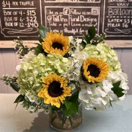 Sunflowers and white hydrangeas arranged in a glass vase