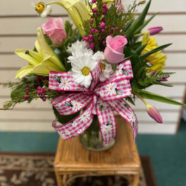 Mixed bouquet in a glass vase with pink ribbon and yellow lilies