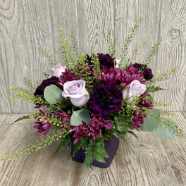 Purple and lavender floral arrangement in a dark vase