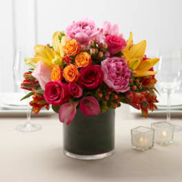 Mixed bouquet of pink, yellow, and orange flowers in a glass vase