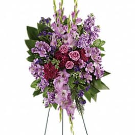 Tall standing spray of purple, lavender, and burgundy flowers on a metal easel