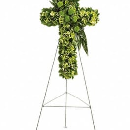 Standing green floral cross on a metal easel with clustered blooms forming the cross shape