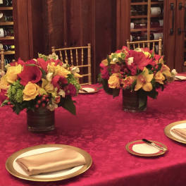 Red and yellow floral centerpieces in dark vases on a banquet table