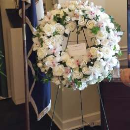 Large white floral wreath on an easel with roses and orchids