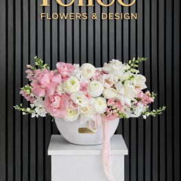 Pink and white floral arrangement in a white vase with a ribbon
