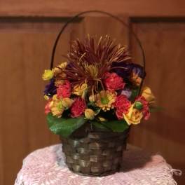 Mixed flowers in a woven basket with a handle