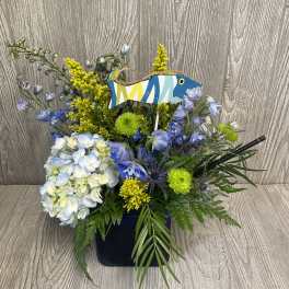Blue and white floral arrangement in a black container with a fish decoration