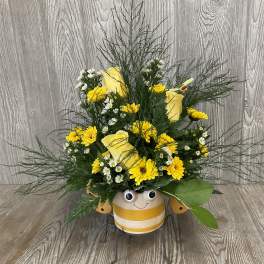Yellow and white flower arrangement in a striped smiling pot