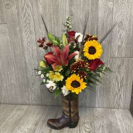 Mixed bouquet with sunflowers, lilies, roses, and cotton in a cowboy boot vase