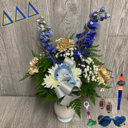 Blue and white floral arrangement in a white vase with a silver ribbon and dolphin accent.
