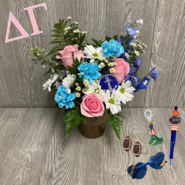 Pink roses, blue carnations, and white daisies in a gold vase