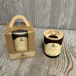 Brown jar candle with engraved wooden lid beside a matching candle in a kraft gift box