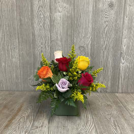Mixed roses in a green square vase with yellow filler flowers