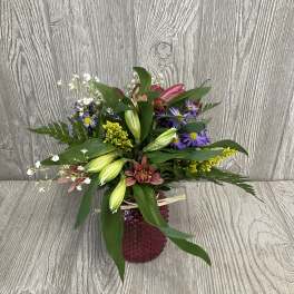 Mixed bouquet in a red textured vase with purple, yellow, and pink flowers