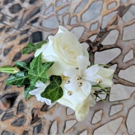 White rose boutonniere with ivy and small white blossoms