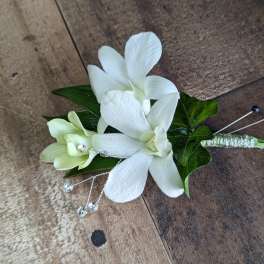 White orchid boutonniere with green leaves and crystal accents