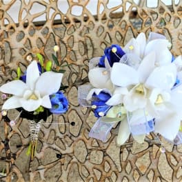 Two white and blue floral boutonnieres with ribbon accents