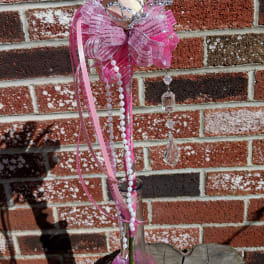 Single pale rose in a tall pink-accented glass bud vase with tiara, bow, pearls, and crystals.