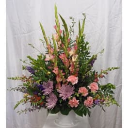 Tall mixed floral arrangement in a white pedestal vase