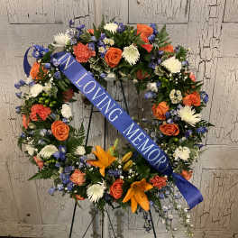 Floral memorial wreath with a blue ribbon reading "IN LOVING MEMORY"