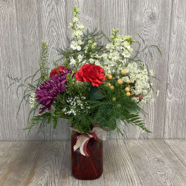 Mixed bouquet in a red glass vase with red, purple, and white flowers