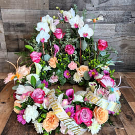 Sympathy wreath of pink roses, white orchids, and mixed blooms with a Loving Mother ribbon.