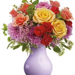 Mixed bouquet of roses and purple flowers in a lavender vase
