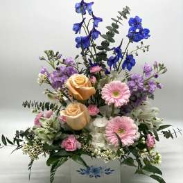 Mixed bouquet in a white box with pink, peach, purple, and blue flowers
