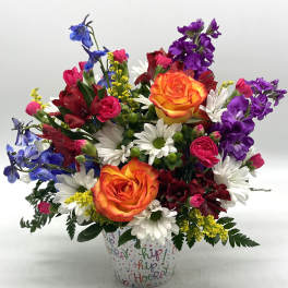 Colorful mixed bouquet in a patterned cup with orange roses and daisies