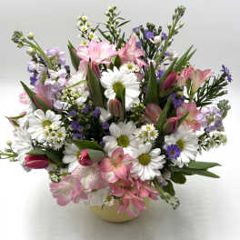 Mixed bouquet of pink lilies, white daisies, and purple filler flowers in a vase