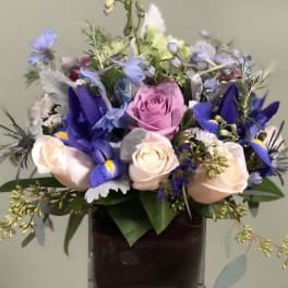 Mixed bouquet of roses and blue flowers in a glass vase