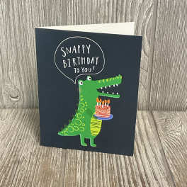 Birthday card with a green cartoon crocodile holding a cake